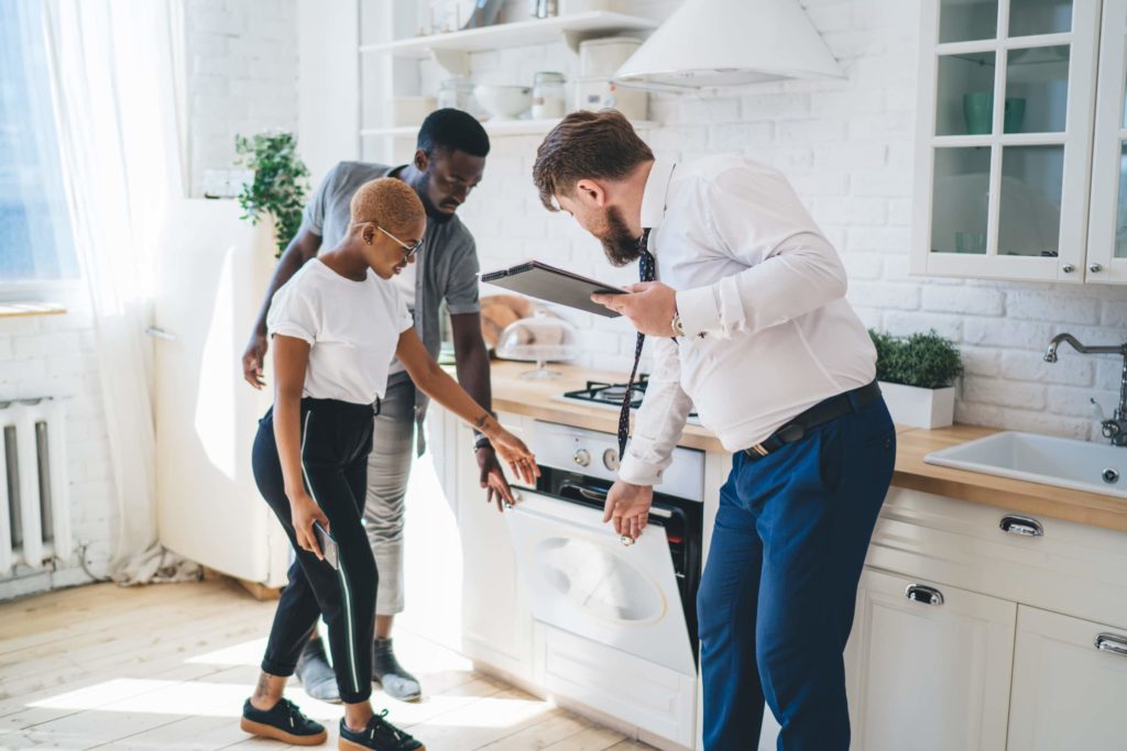 Confident estate agent showing kitchen to African American thoughtful couple; property management careers