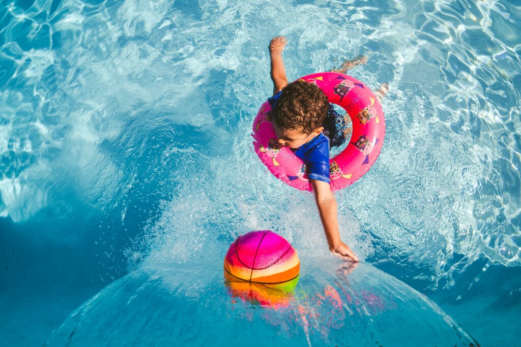child playing in the water with pool toys