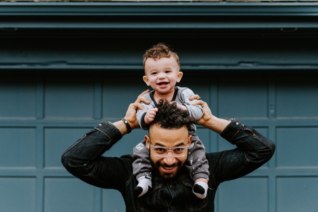 man carrying a child on his shoulders while both smile