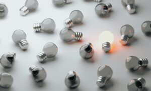 Many burnt out light bulbs with one lit light bulb to the right