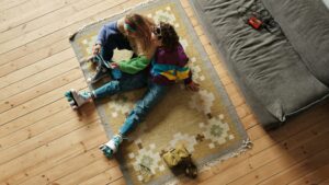 Two individuals sitting on the floor of their apartment on a no-slip area rug bought off Amazon